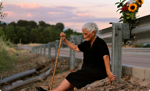 Ηλικιωμένη γυναίκα καθισμένη δίπλα σε επαρχιακό δρόμο